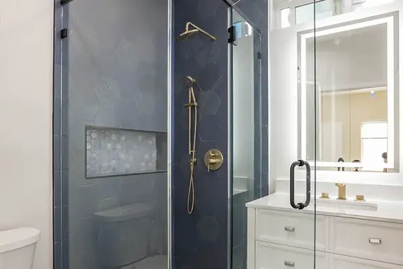 Navy hexagonal-tiled shower with brass fixtures inside a completed H&A ADU.