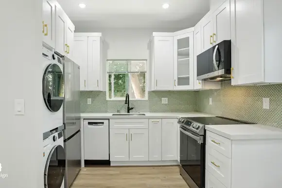 ADU kitchen with white cabinetry and a stacked washer and dryer built in.