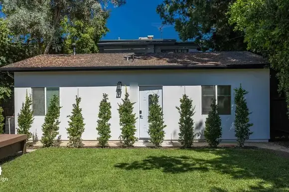 Exterior of a finished ADU with a hedge screen and lawn.
