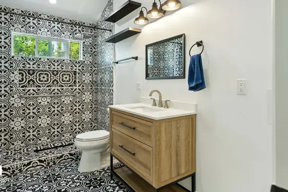 Timber vanity and patterned floor tile in a completed ADU bathroom.