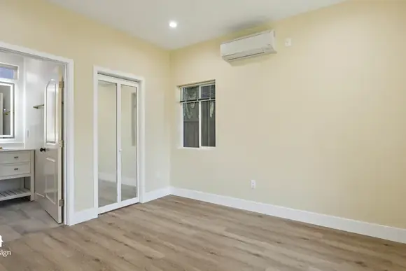 Bedroom in a completed ADU with wall-mounted air conditioning and a closet.