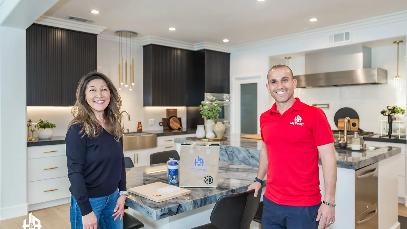 An H&A My Design team member in a branded company shirt standing with a homeowner in a completed kitchen.