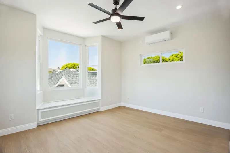 Bright, newly finished ADU room with a ceiling fan and wall-mounted air conditioning.