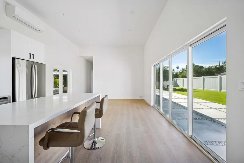 ADU interior with a vaulted ceiling, long counter with stools and sliding doors to the garden.