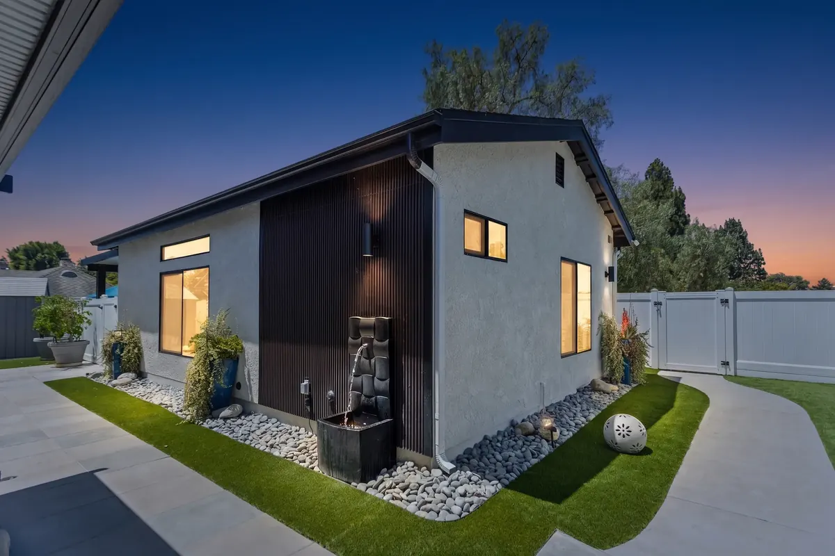 A completed detached ADU by H&A My Design photographed at dusk, with lit windows, timber slat cladding and landscaped surrounds.